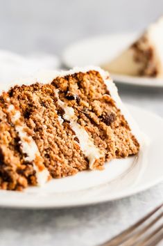 a slice of carrot cake on a white plate with a fork next to the rest of the cake