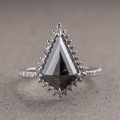 a black and white diamond ring sitting on top of a gray surface with diamonds around it