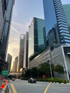 cars driving down the street in front of tall buildings with skyscrapers on either side