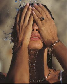 a woman with her hands on her face and water splashing all over her head