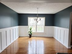 an empty room with blue walls and white trim on the walls, wood flooring