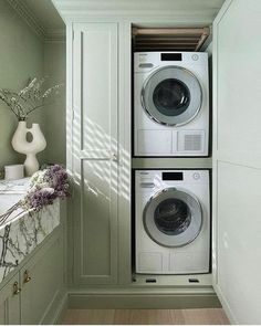 a washer and dryer are in the corner of a room with green walls