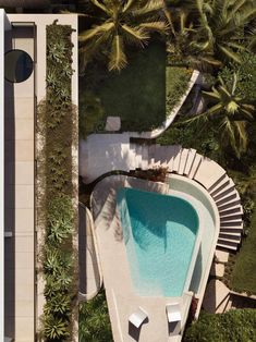 an aerial view of a swimming pool surrounded by palm trees and greenery in the foreground