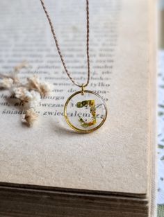 This handmade resin necklace is filled with real flowers and petals, perfectly accompanied by sparkles of 24k gold leaf. Finished and set on 16inch fine cord for a dainty, minimalistic look. The gold bezel and clasp are made of hypoallergenic stainless steel.  Each gift is lovingly packaged in a natural eco box, wrapping paper or a bag, ready for gift giving. My products are 100% handmade by me, from collecting flowers, and other organic matters, to casting resin, and finishing with sanding and Adjustable Nature-inspired Necklace With Pressed Flowers, Gold Charm Necklace With Pressed Flowers In Round Pendant, Nature-inspired Yellow Necklace For Gifts, Adjustable Gold Necklace With Birth Flower, Yellow Nature-inspired Necklace For Gifts, Handmade Gold Resin Necklaces, Yellow Round Pendant Necklace As Gift, Yellow Round Pendant Necklace For Gift, Adjustable Round Pendant Necklace With Pressed Flowers