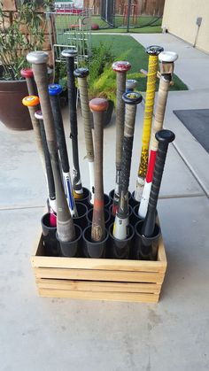 a wooden box filled with baseball bats on top of a cement floor next to a building