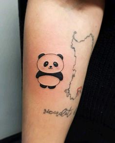 a small panda bear tattoo on the arm