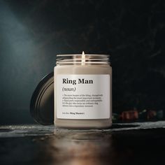 a candle sitting on top of a table next to a black wall with the words ring man printed on it