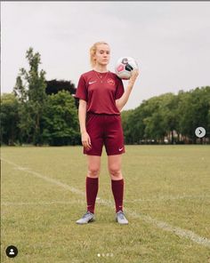 a woman in red uniform holding a soccer ball