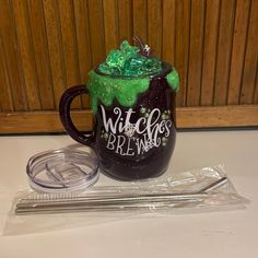 a glass mug with green liquid sitting on top of a table next to a straw