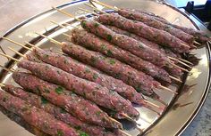 several skewers of meat are on a metal platter, ready to be grilled