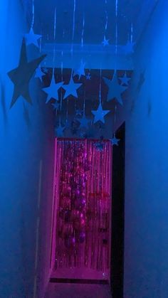 a hallway with stars hanging from it's ceiling and pink curtains on the wall