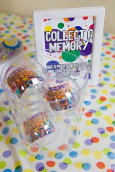 three plastic cups filled with candy sitting on top of a polka dot tablecloth covered table