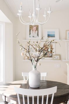 a white vase filled with flowers sitting on top of a table next to a chandelier