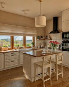 a kitchen with an island and two chairs in front of the stove top ovens