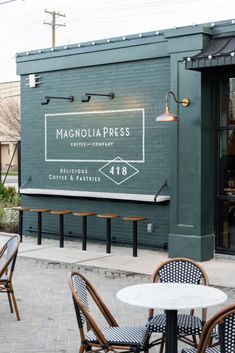 tables and chairs outside of a restaurant with the sign for magnolia press coffee company on it