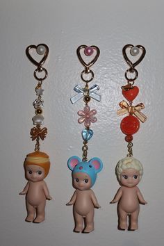 three key chains with little dolls attached to them