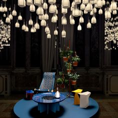 a blue table with some lights hanging from it's ceiling and chairs around it