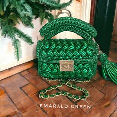 a green handbag sitting on top of a tile floor next to a tree and door