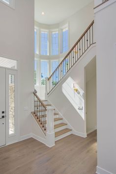 an empty room with white walls and wood floors, stairs leading up to the second floor