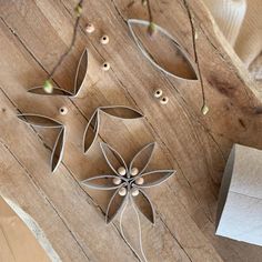 three metal flowers sitting on top of a wooden table next to a piece of paper