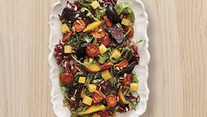 a white plate topped with salad on top of a wooden table