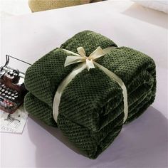 two folded green towels on top of each other with a white ribbon tied around them