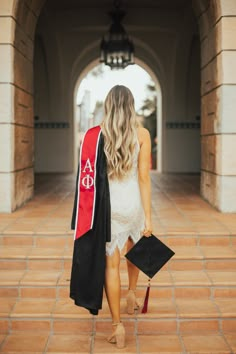 a woman walking down a walkway with her graduation cap and gown