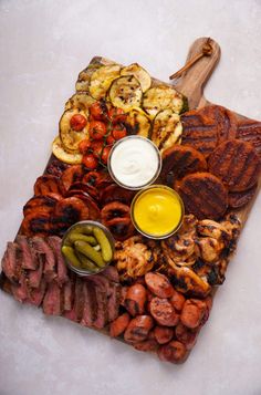 an assortment of meats and vegetables on a cutting board