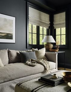 a living room with black walls and white furniture in the corner, along with two large windows