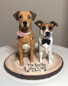 two figurines of dogs sitting on top of a cake