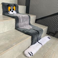 a cat rug is on the stairs with it's eyes open and paws down