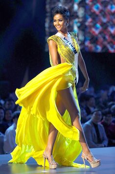 a woman in a yellow dress walks down the runway wearing high heels and a tiara