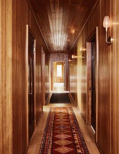 the hallway is lined with wooden paneling and has a red runner rug on it