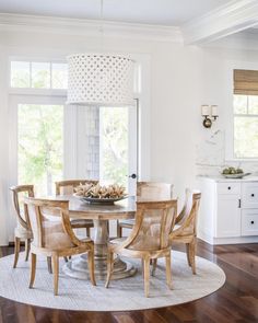 a dining room table and chairs in front of a window with white trim on the walls