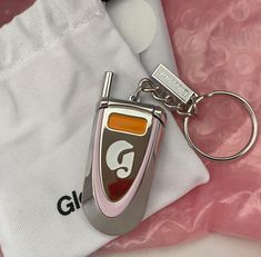 a close up of a keychain on a pink and white cloth with a bag in the background