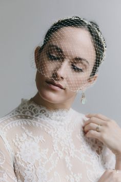 a woman is wearing a veil over her head and looking down at the top of her dress