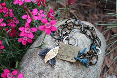 a rock with some charms on it and flowers in the background