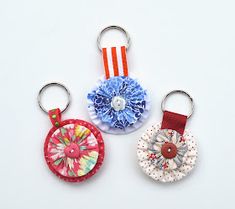 three keychains with different designs on them sitting next to each other in front of a white background