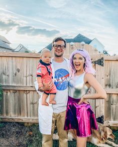 a man, woman and child posing for a photo in front of a wooden fence