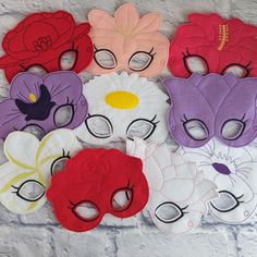 a bunch of masks that are sitting on a wall with flowers in the middle and one has eyes closed