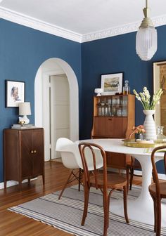 a dining room with blue walls and white furniture