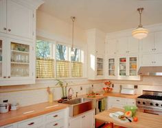 a kitchen with white cabinets and wooden counter tops