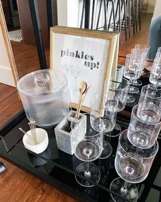 there are many glasses on the table with gold spoons in them and a sign that says pinkies tup?