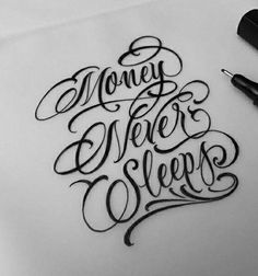 some type of lettering that is on top of a paper with pen and ink next to it