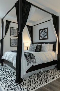 a black and white bedroom with four poster bed