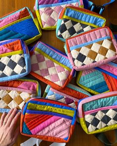 several colorful handbags sitting on top of a wooden table