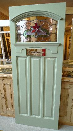 a green door with stained glass on the top and bottom panel, in front of some cabinets