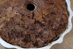 a chocolate cake in a white dish on a wooden table