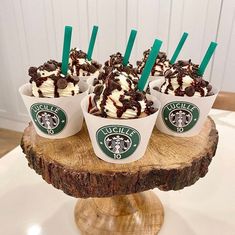 four cups filled with ice cream and chocolate on top of a tree stump cake stand