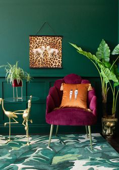 a living room with green walls, purple chair and potted plant in the corner